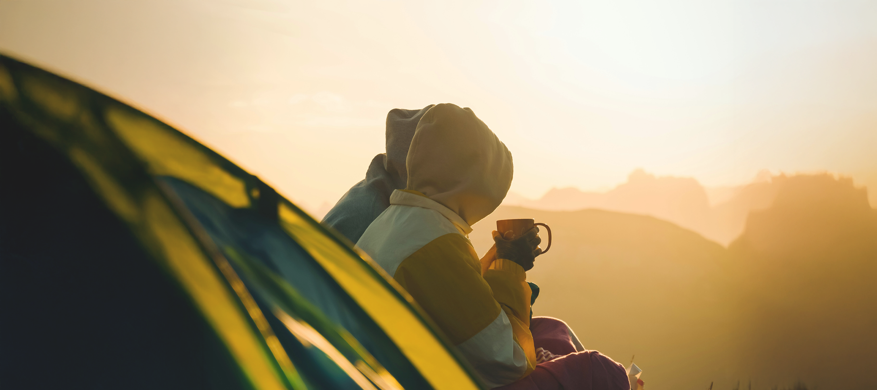 Two people sitting in a car looking at a scenic sunset drinking Ffee & Co coffee